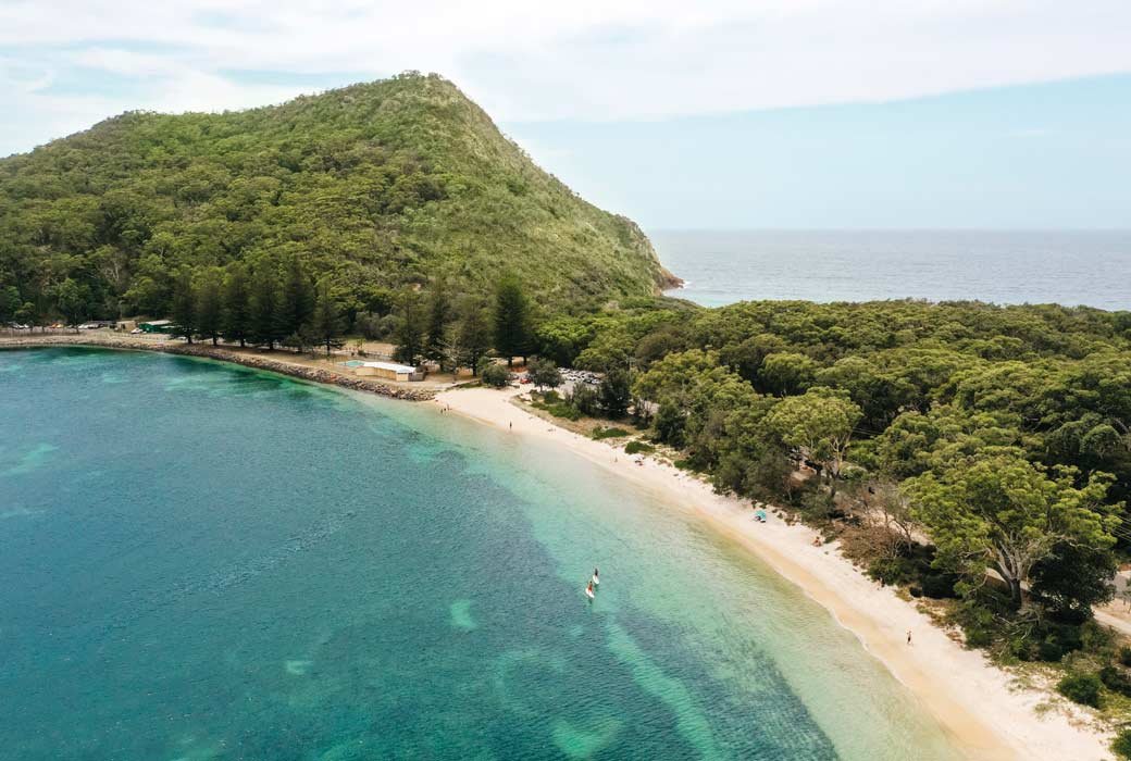 Couple enjoying a stand up paddleboarding experience in Shoal Bay, Port Stephens.