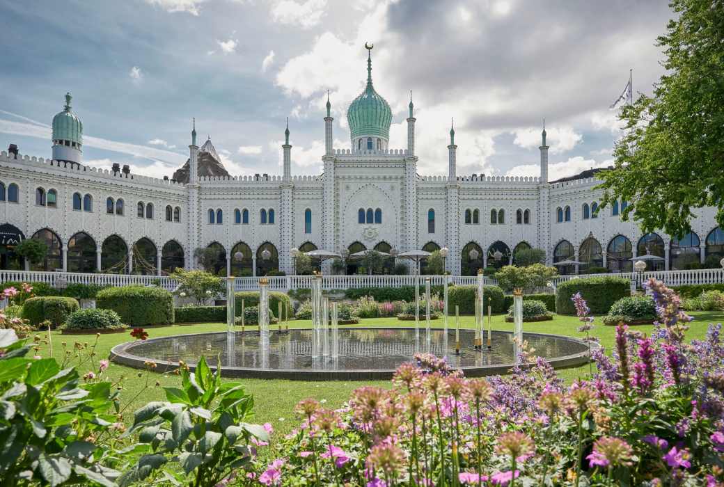A manicured lawn and water fountain with a castle in the background