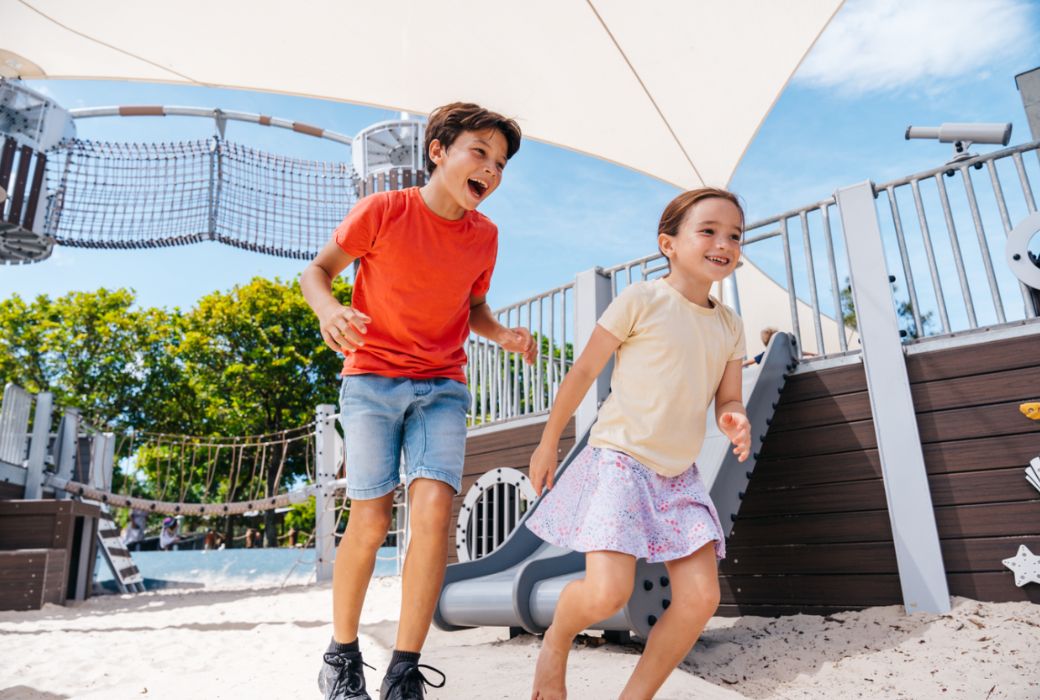 Two kids laughing and running in playground