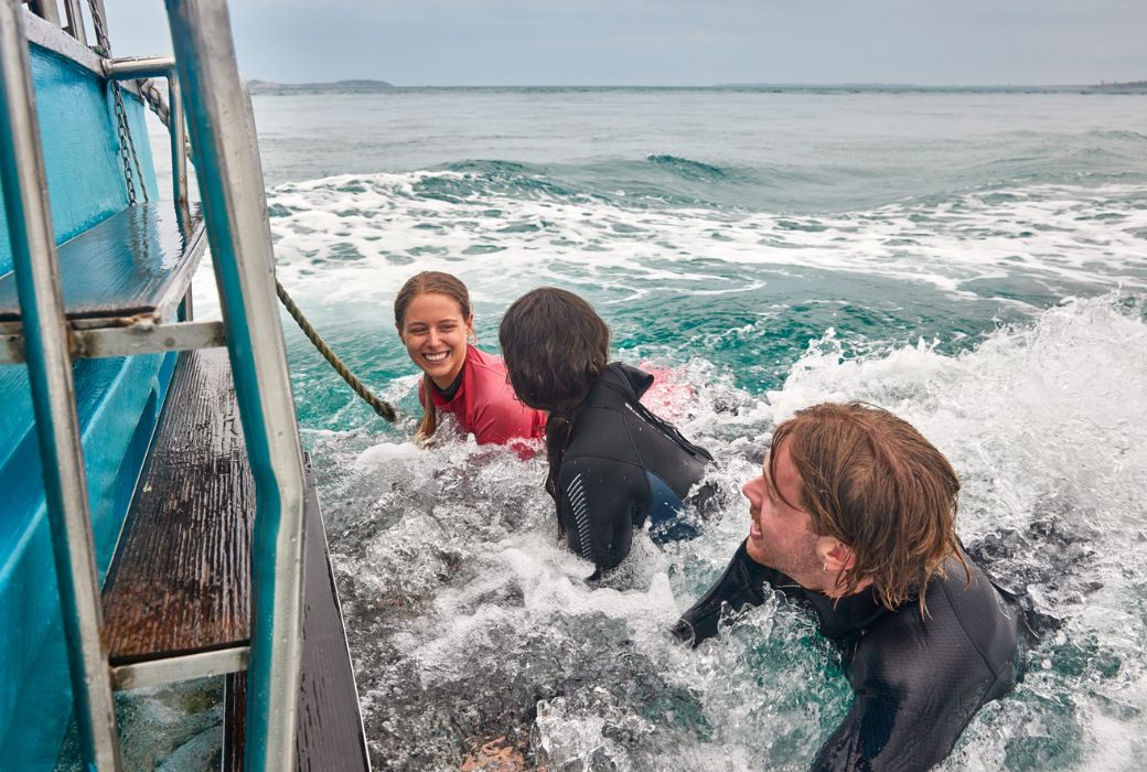 swimmers hanging onto back of boat