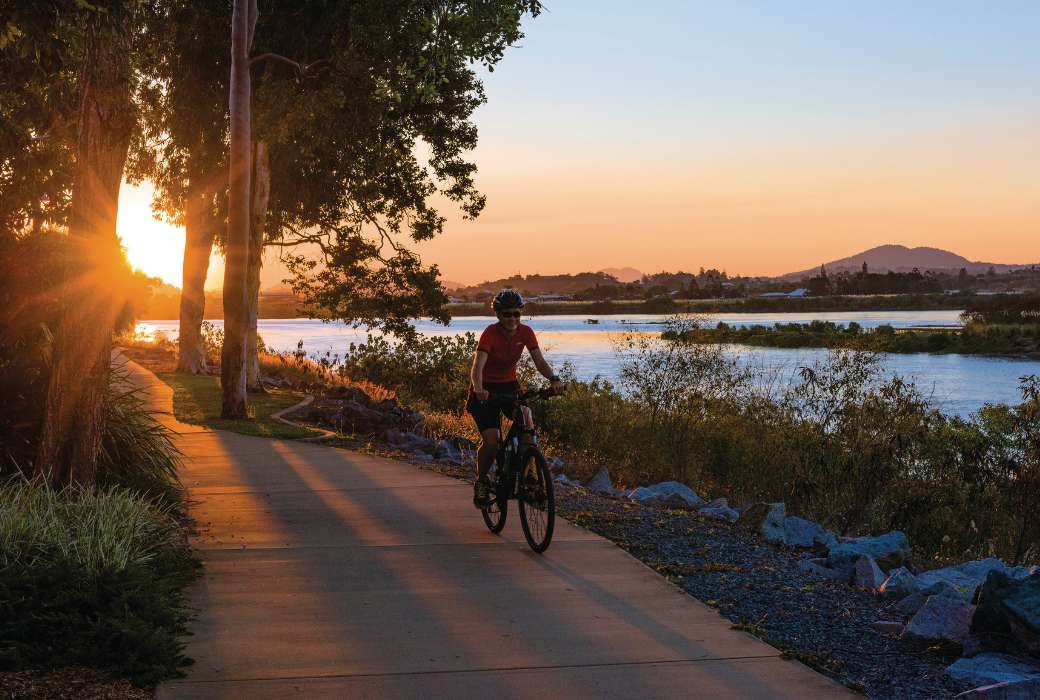 A person cycling on a path alongside a river