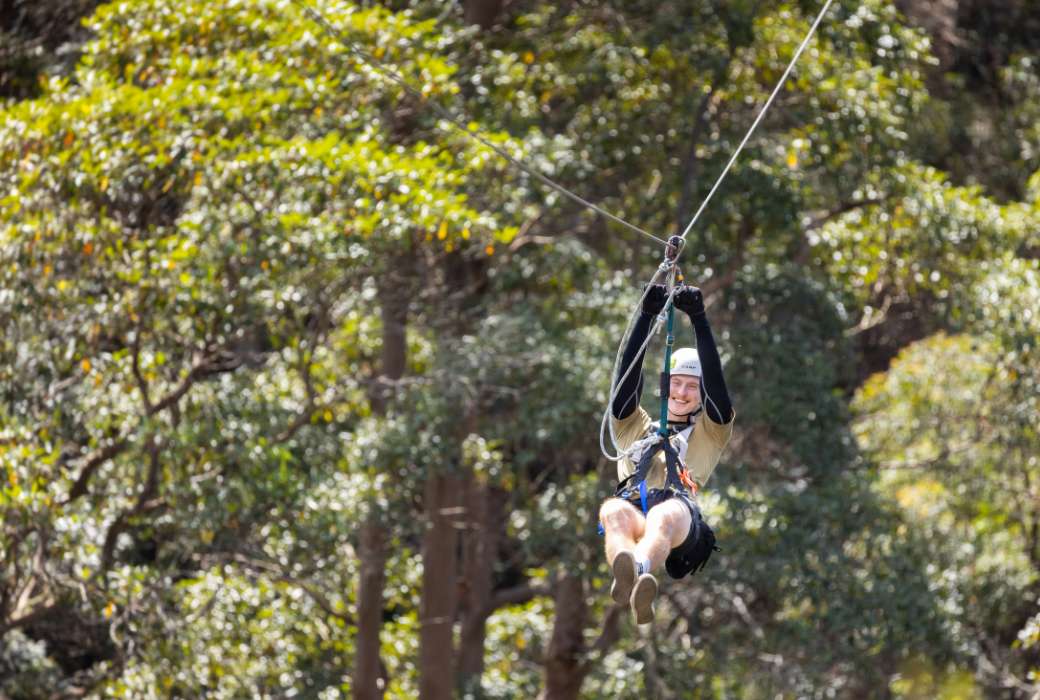 A person ziplining above the treetops