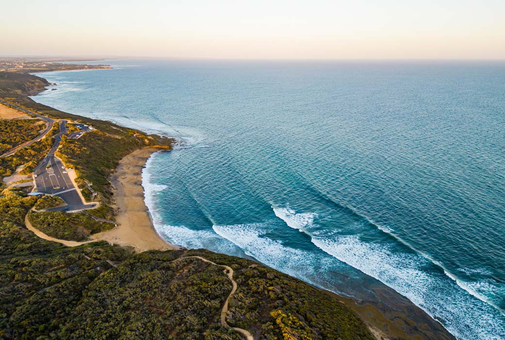 An aerial view of waves hitting Bells Beach at sunset in Torquay, Victoria, Australia.